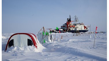 Blick auf ein Eiscamp in der Arktis mit Forschungsschiff im Hintergrund | © Michael Gutsche
