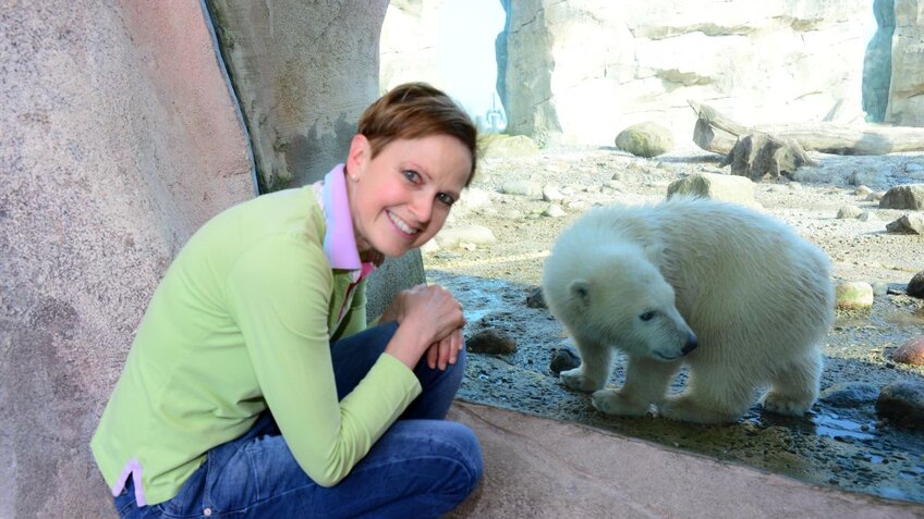 Ein Frau kniet vor einer Scheibe, dahinter befindet sich ein Eisbär. | © Zoo am Meer