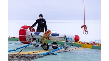 Ein junger Mann mit Mütze steht vor einem Forschungsinstrument | © Mario Hoppmann