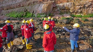 Eine Gruppe Menschen mit gelben Helmen im Felswatt vor Helgoland | © Uwe Nettelmann