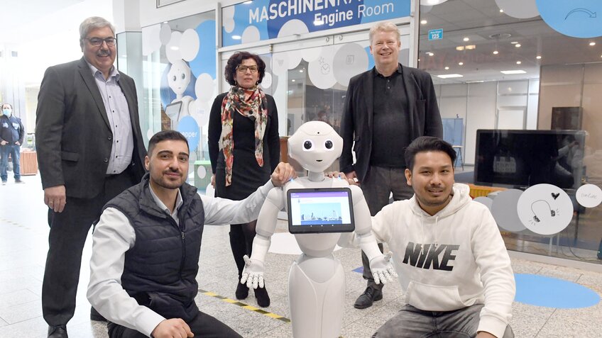 5 Menschen und ein weißer Roboter stehen und knien zu einem Foto zusammen. | © Wolfhard Scheer