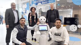 5 Menschen und ein weißer Roboter stehen und knien zu einem Foto zusammen. | © Wolfhard Scheer