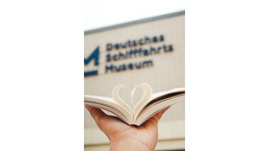 Eine Hand hält ein Buch in der Hand, wobei die Seiten zu einem Herz gefaltet sind.  | © Pravin Vijayakumar