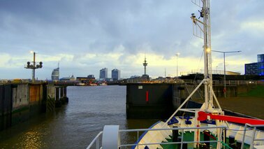 Ein Schiff steht vor der Schleuse mit dem Blick auf die Stadt bei Abenddämmerung.   | © Cornelia Riml