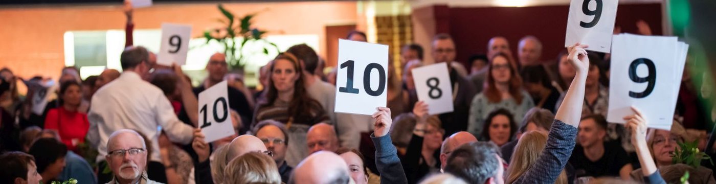 Menschen stimmen in einem Saal ab.