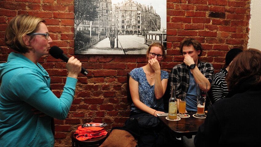 Eine Frau mit einem Mikrofon befragt zwei Zuhörer, die sich die Nase zuhalten.  | © Jens Rillke
