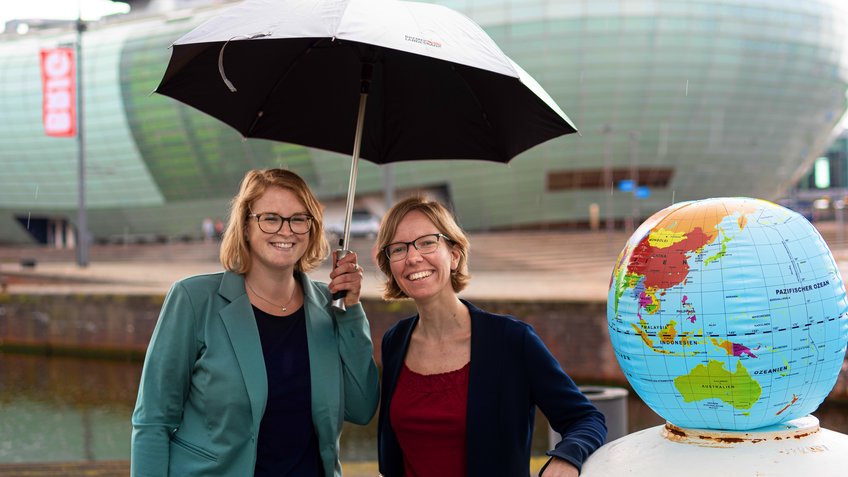 Zwei Frauen mit einem Regenschirm und einem Globus.  | © Hannes Voigts