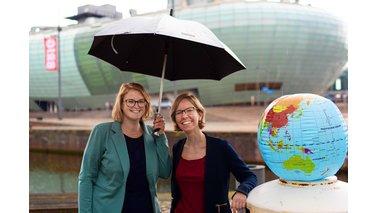 Zwei Frauen mit einem Regenschirm und einem Globus.  | © Hannes Voigts