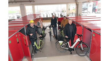 5 Menschen stehen mit ihren Fahrrädern vor roten Fahrradboxen. | © Wolfhard Scheer