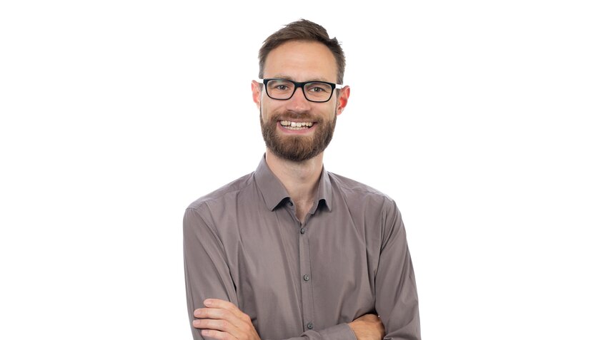 Das ist ein Bild von Thorsten Friedrichs, ein Junger Mann mit Bart und Brille, außerdem einem Strahlenden Lächeln. 