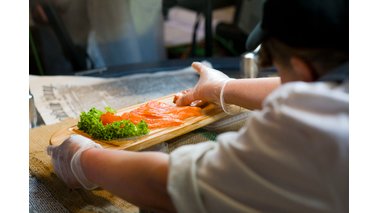 Eine Person richtet Lachs auf einer Platte an