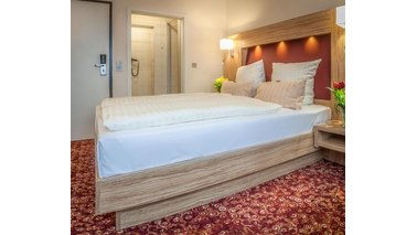 Ein großes Bett in einem Doppelzimmer des City-Hotel-Bremerhaven