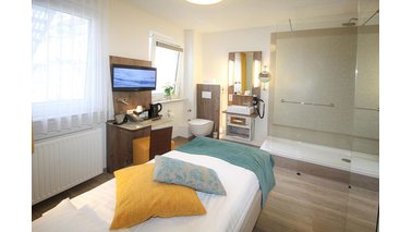 Ein Einzelzimmer mit Bett, Dusche und Fernseher im City-Hotel-Bremerhaven