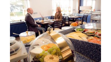 Eine Käseglocke und gedeckter Tisch im Frühstücksraum des City-Hotel-Bremerhaven
