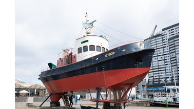 Ein Schlepper steht über Wasser als Exponat im Museumshafen. 