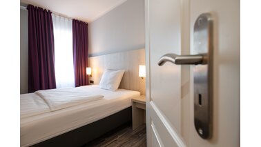 Bild eines Bettes für eine Person in einem Hotel.